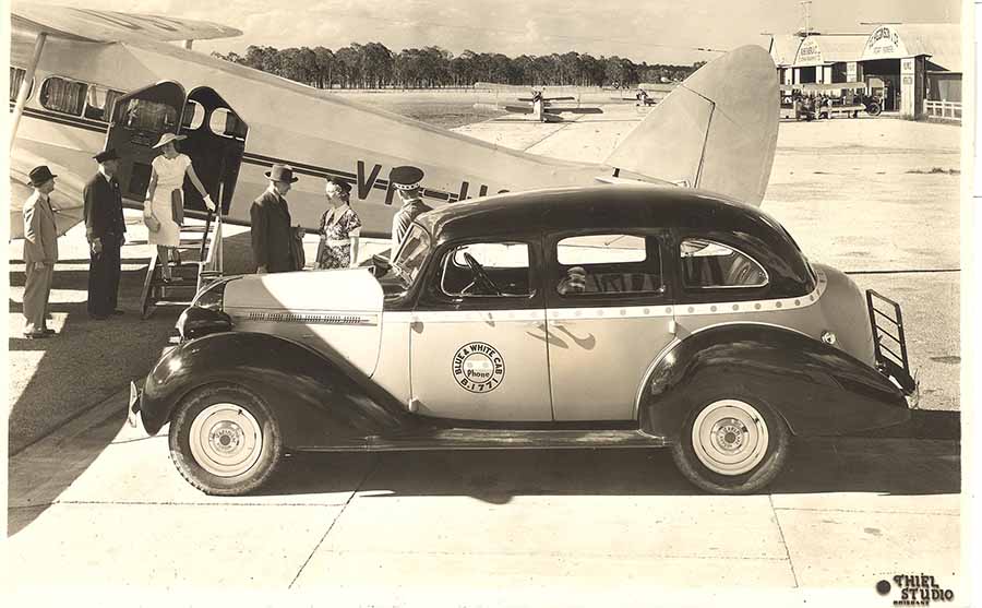 A Qantas publicity photo taken at Archerfield Airport in Brisbane in 1936 showing a DH86 with a Hudson Terraplane taxi copy